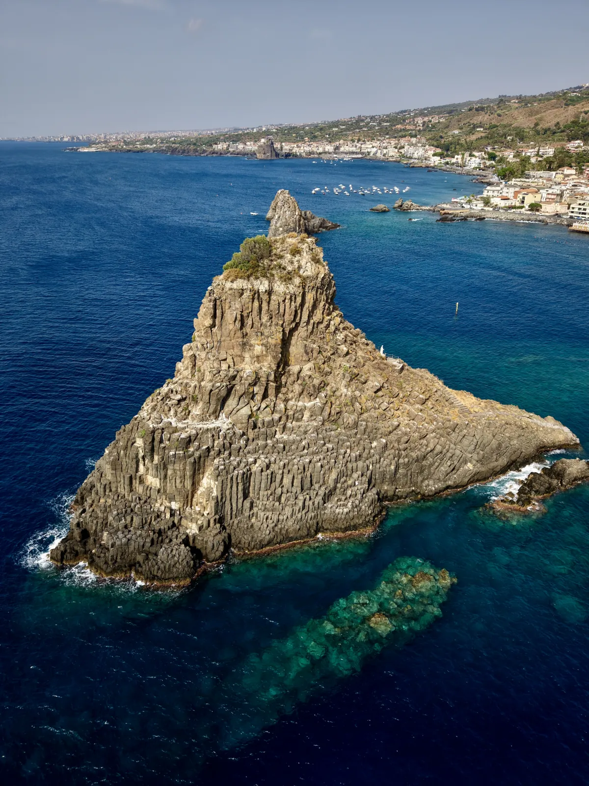 Il Faraglione Grande di Acitrezza visto dall'alto, con le colonnate di basalto e la costa sullo sfondo