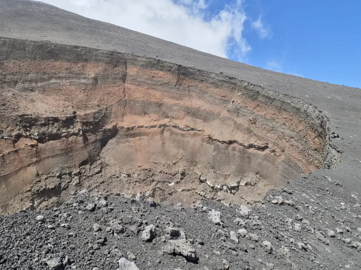 Il bordo di un pit crater sull'Etna: il terreno arriva al ciglio e si interrompe di netto, senza cumuli di cenere o lapilli